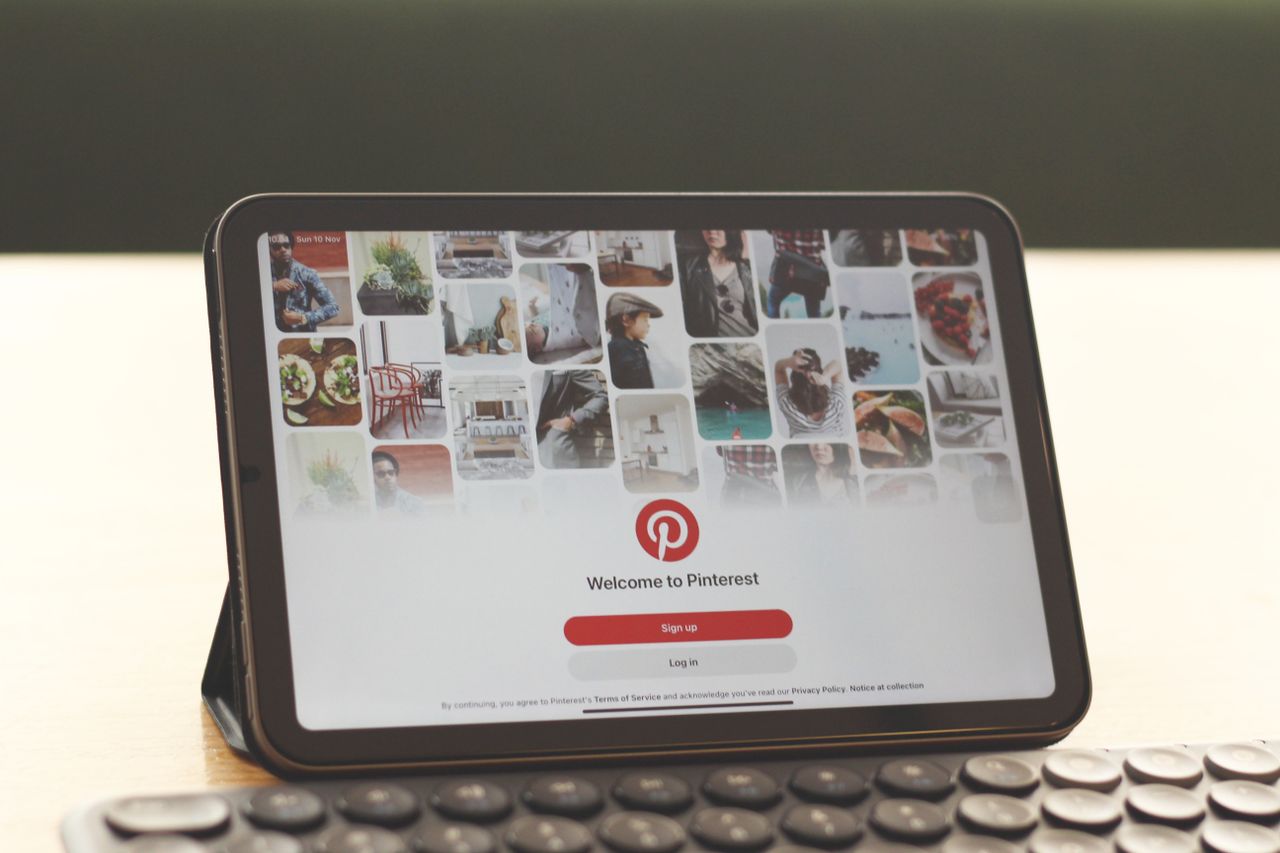 Tablet showing Pinterest homepage on a modern desk setup with a keyboard.